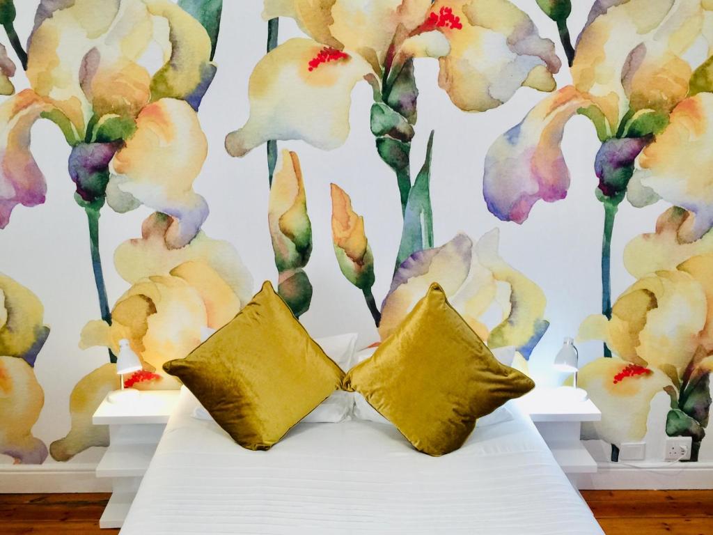 a bed with two pillows in front of a floral wall at Mediterranean Villa Guesthouse in Cape Town