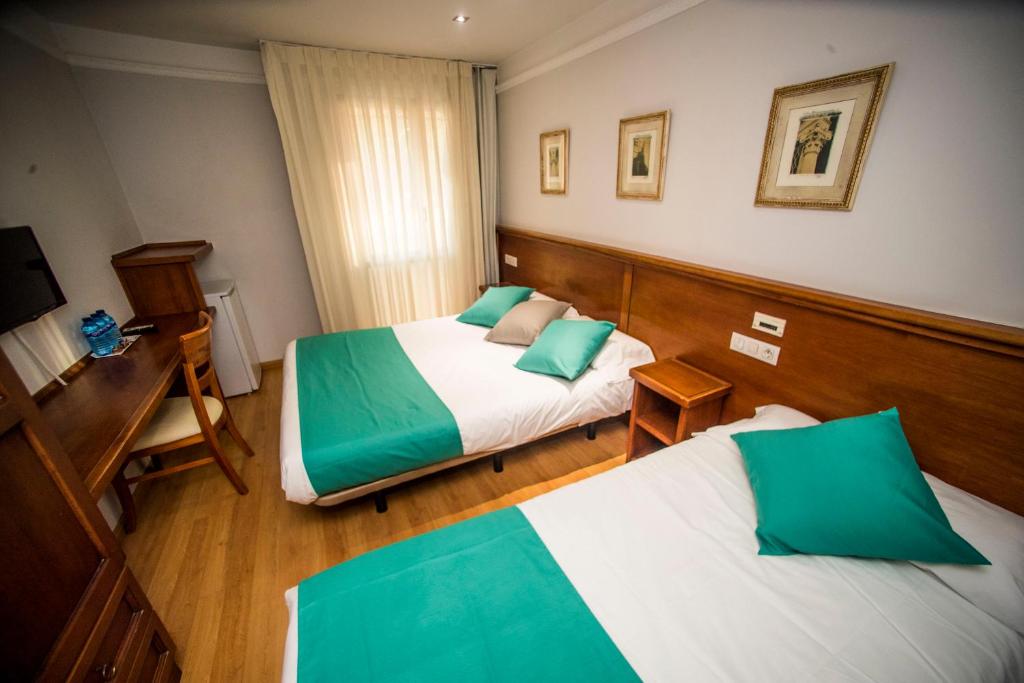 a hotel room with two beds and a desk at Hotel Alba in Soria