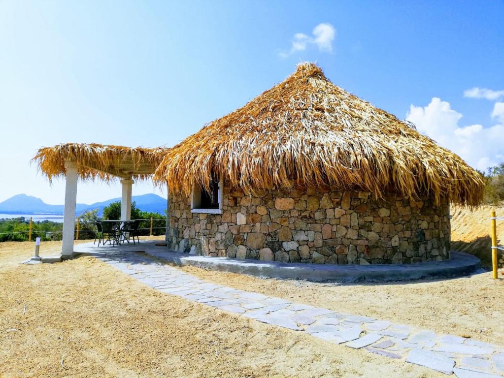 Cabaña pequeña con techo de paja y mesa en Agriturismo Dolceluna Le Capanne en Muravera