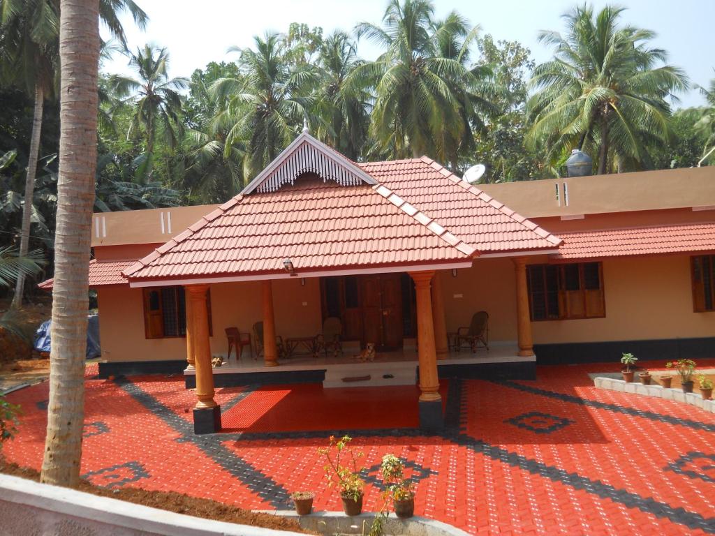 ein Haus mit einem roten Dach und Palmen in der Unterkunft CoconutCrazy! Homestay in Ottappālam