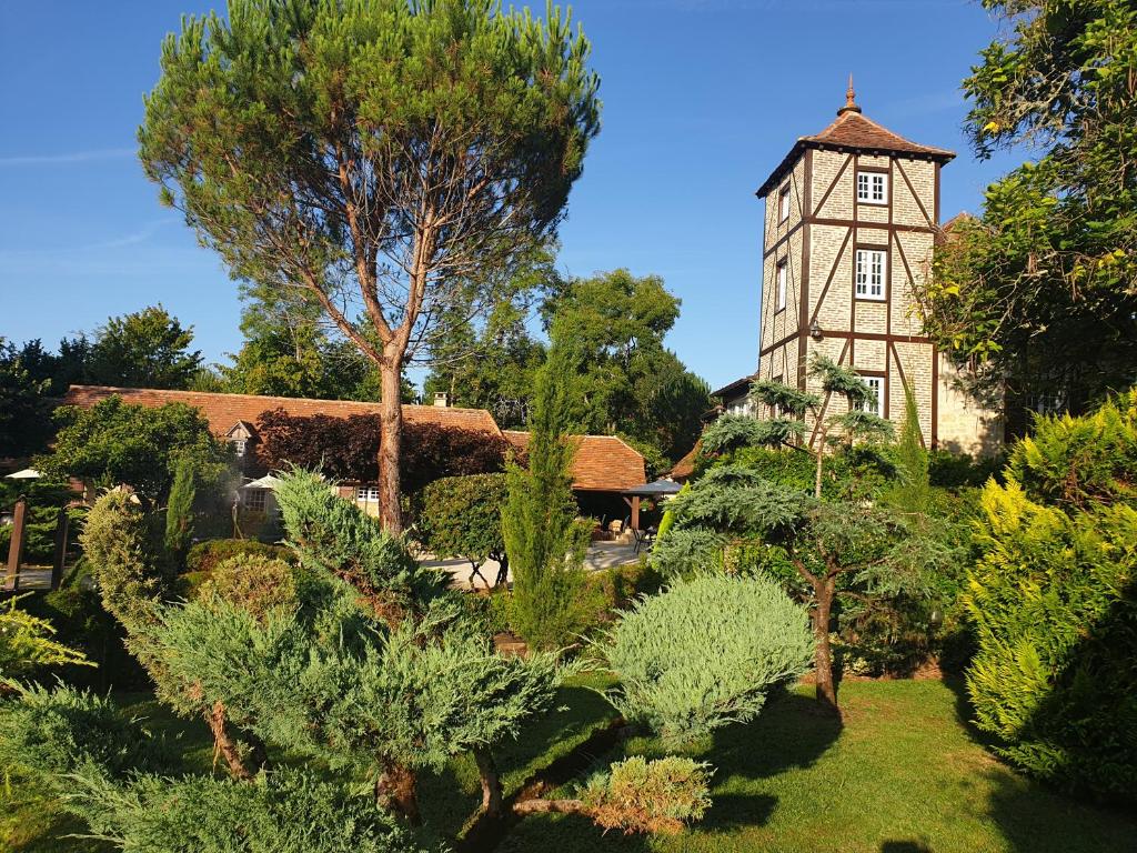 an old building with a tower in a garden at Moulin du soustre in Cavagnac