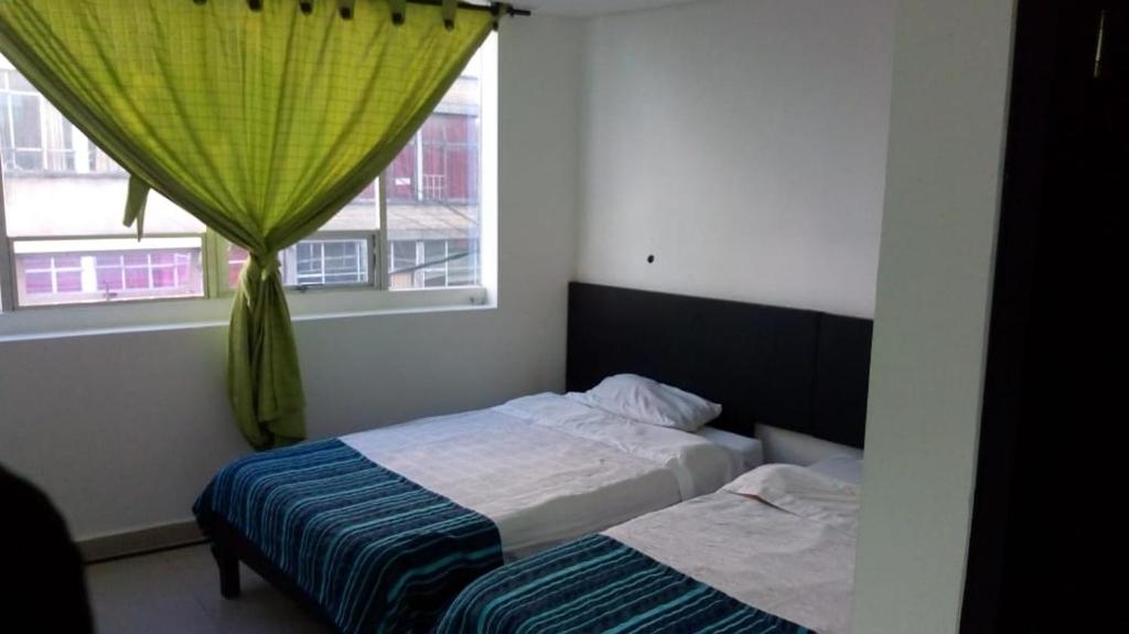 a bedroom with two beds and a window at Hotel Santafe Suite in Bogotá