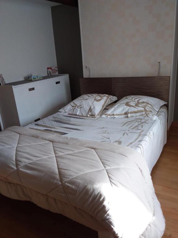 Una cama blanca con cabecero de madera en un dormitorio en Chez Christian, en Auxonne