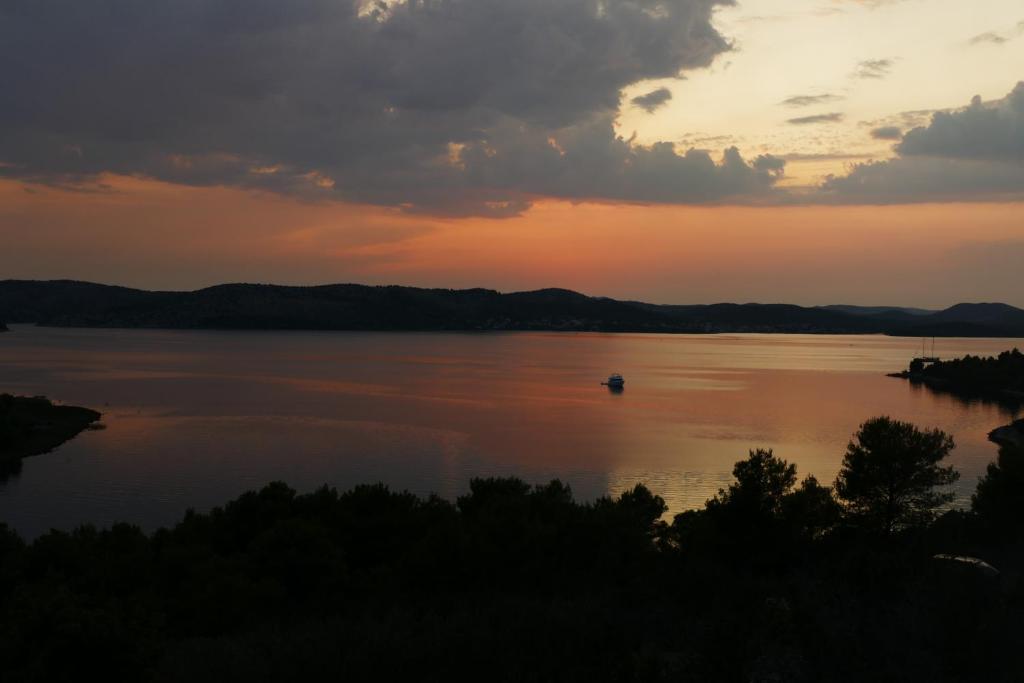 een zonsondergang op een meer met een boot in het water bij Infinity in Šibenik