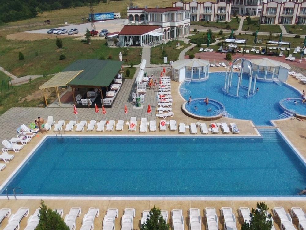 a large swimming pool with umbrellas and chairs in a resort at Апартаментен туристически комплекс Аква Терми in Krasnovo