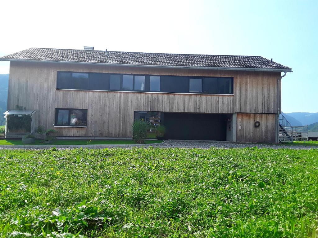 a house with a large garage in front of a field at Appartment Hirschberg in Bizau