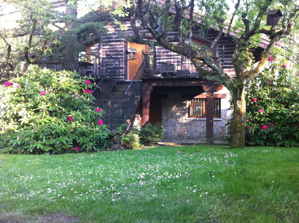 ein Haus mit einem Baum und Blumen im Hof in der Unterkunft Hotel Rural Los Frutales in Cercedilla