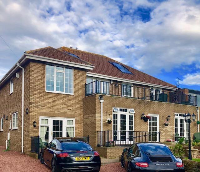 two cars parked in front of a brick house at Westlea Guest House in Alnmouth