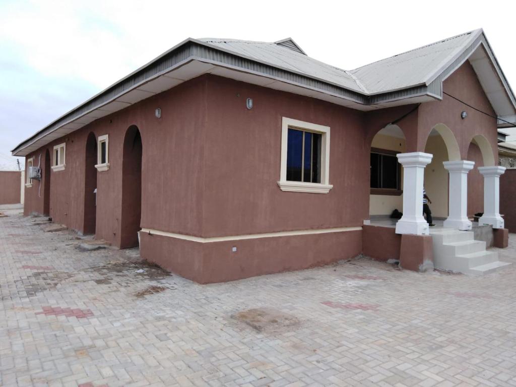 a brown house with a brick driveway at TJ Cottage in Ilorin