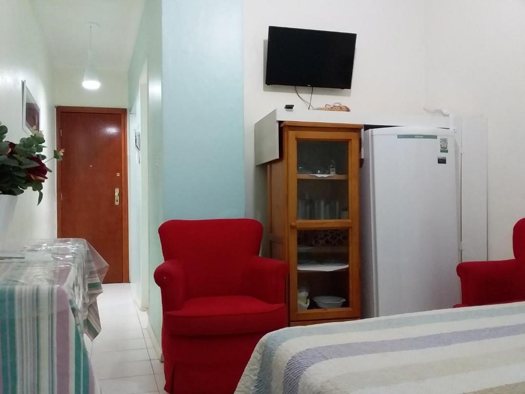 ein Wohnzimmer mit einem roten Stuhl und einem Kühlschrank in der Unterkunft Apartamento Copacabana 8 in Rio de Janeiro