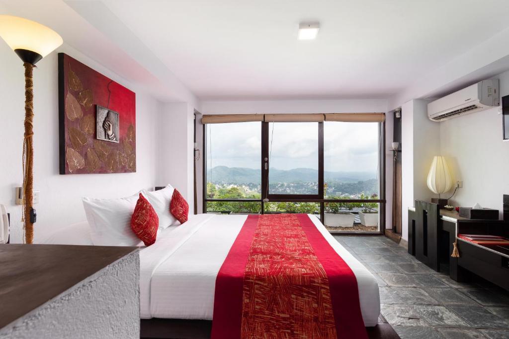 a bedroom with a large bed and a large window at The Theva Residency in Kandy