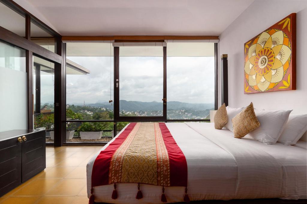 a bedroom with a large bed with large windows at The Theva Residency in Kandy