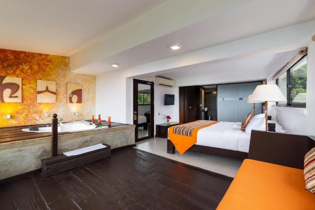 a hotel room with a king bed and a tub at The Theva Residency in Kandy