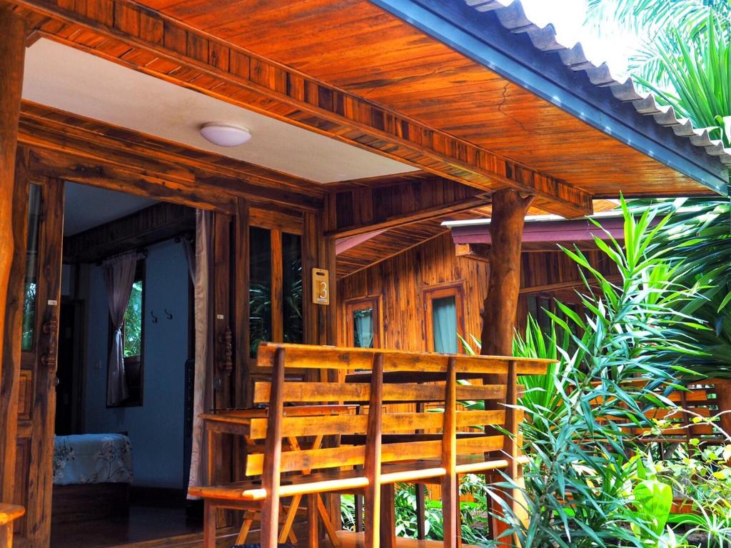 a wooden deck with a bench on a house at Baansuan Resort in Don Sak