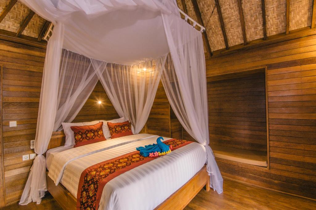 a bedroom with a bed with an elephant toy on it at Nerima Hut Lembongan in Nusa Lembongan