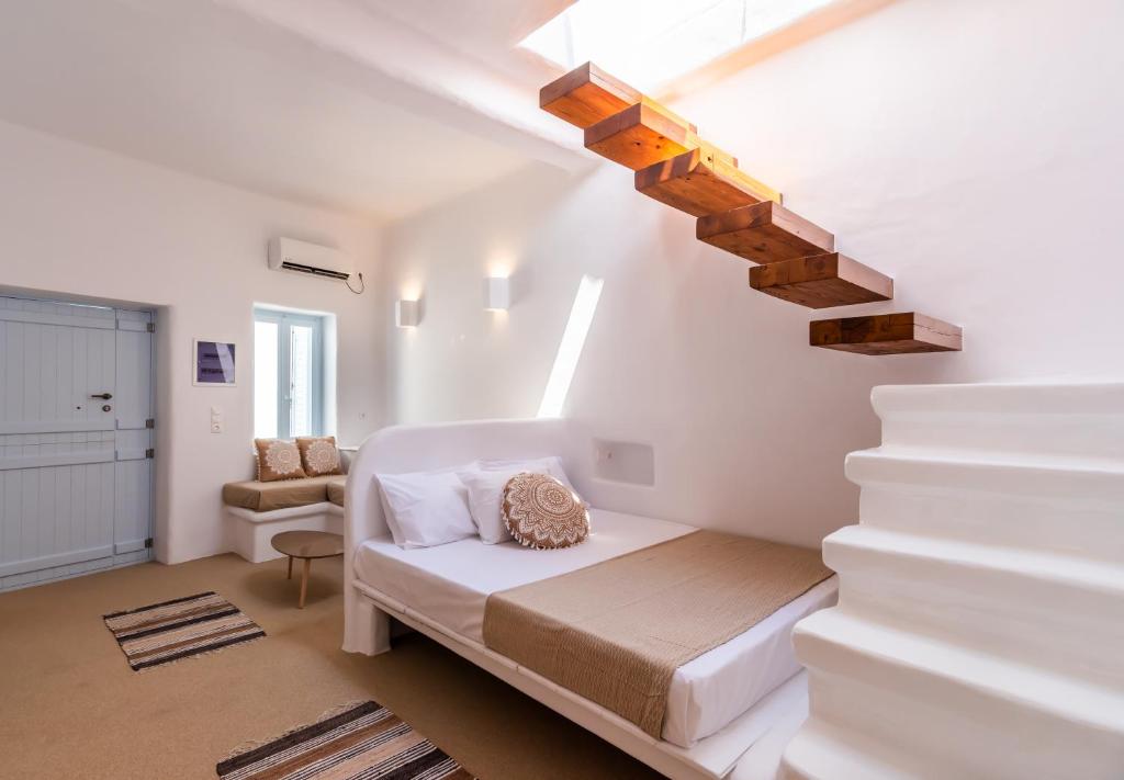 a white room with a bed and a staircase at Sunset Nest in Plaka Milou