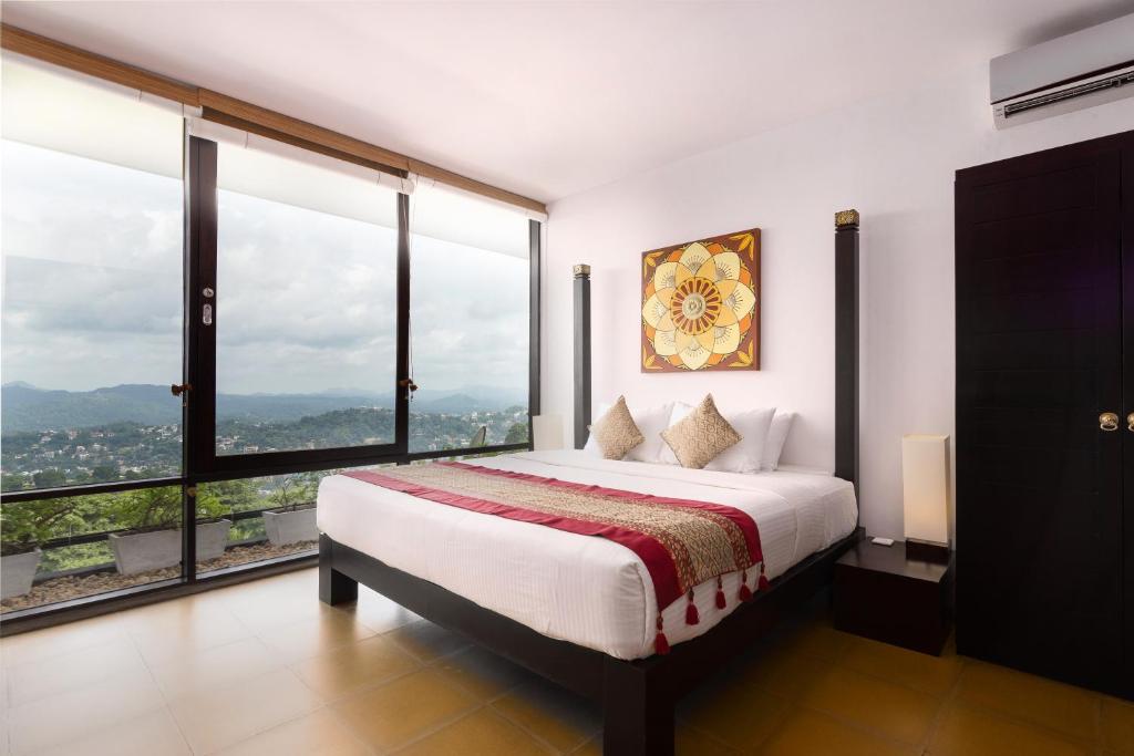 a bedroom with a large bed with large windows at The Theva Residency in Kandy