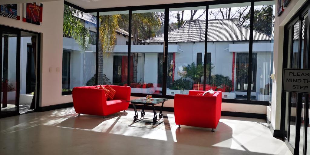 ein Wohnzimmer mit 2 roten Stühlen und einem Tisch in der Unterkunft 21 Kingfisher Guesthouse in Johannesburg