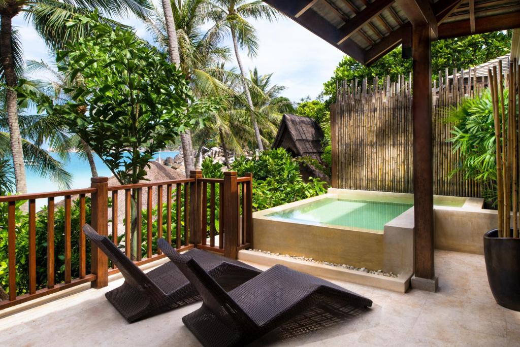 a deck with black chairs and a swimming pool at Anantara Rasananda Koh Phangan Villas in Thong Nai Pan Noi