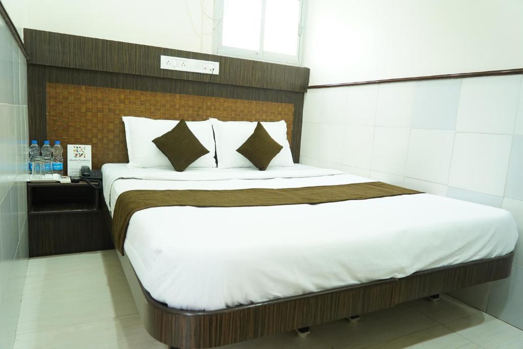 a bedroom with a bed with white sheets and pillows at Sharda Residency in Mumbai