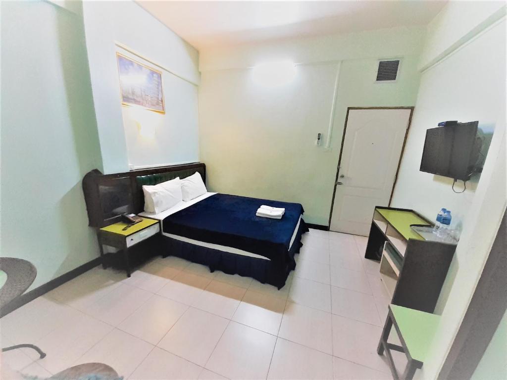 Dormitorio con cama, escritorio y TV en Singapore Hotel, en Hat Yai