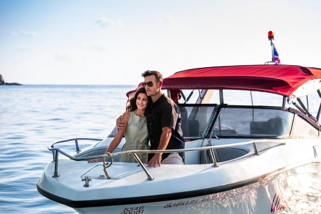 a man and woman standing on a boat in the water at Anantara Rasananda Koh Phangan Villas in Thong Nai Pan Noi