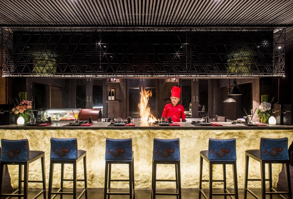 a chef standing behind a kitchen counter with a fire at Anantara Rasananda Koh Phangan Villas in Thong Nai Pan Noi