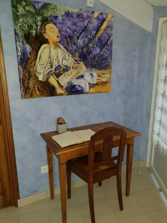 a desk with a painting on the wall next to a table with a chair at Chambre d&#39;hôtes Esterelle in Pernes-les-Fontaines