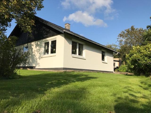 a white house with a large yard in front of it at Det Bette Hus in Hjørring