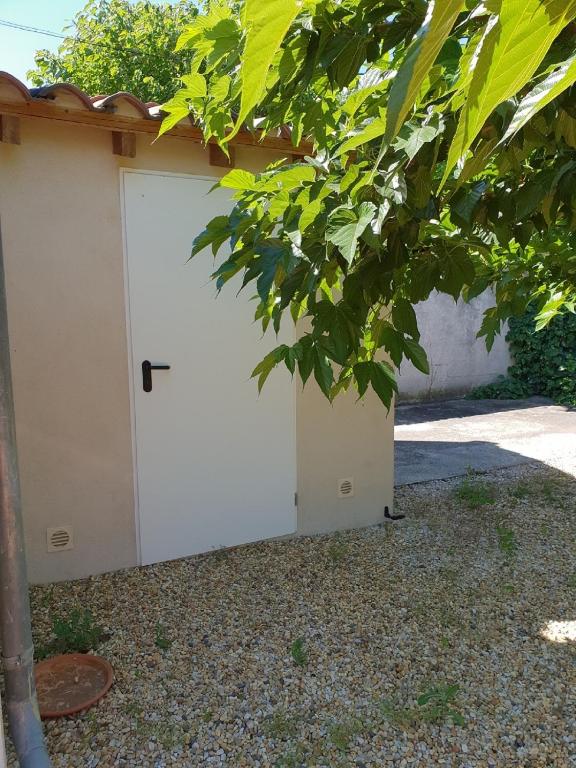a white garage door with a tree in the foreground at Chambre d&#39;hôtes Esterelle in Pernes-les-Fontaines