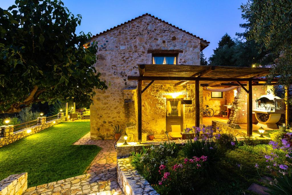 une maison en pierre avec un jardin la nuit dans l'établissement Vrisali Traditional Stone Villa, à Yerolákkos