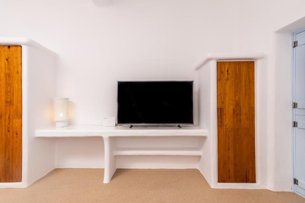 a living room with a tv on a white desk at Sunset Nest in Plaka Milou