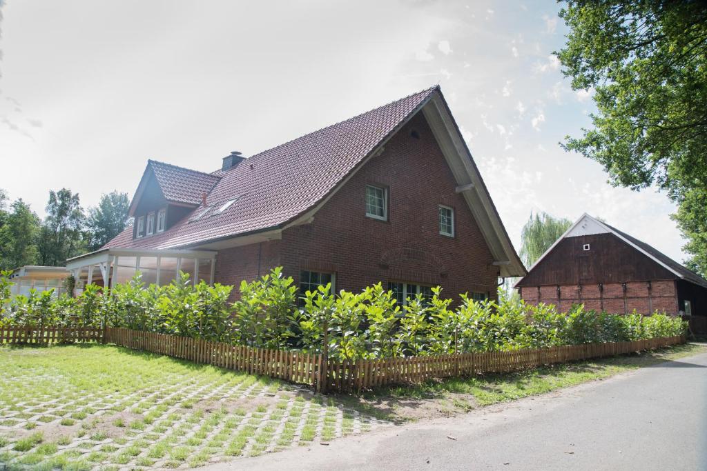 une grande maison en briques avec une clôture devant elle dans l'établissement Oelgemoellers Hus, à Lohne