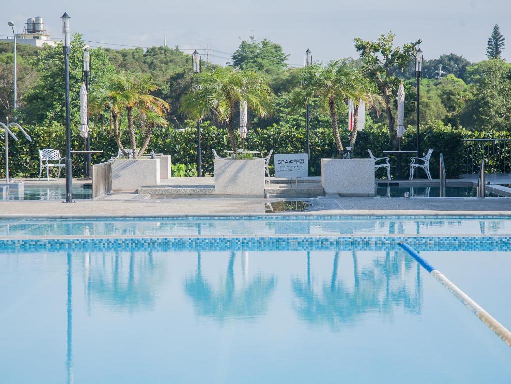 a swimming pool with blue water and palm trees at Freshfields Hotel in Wuri