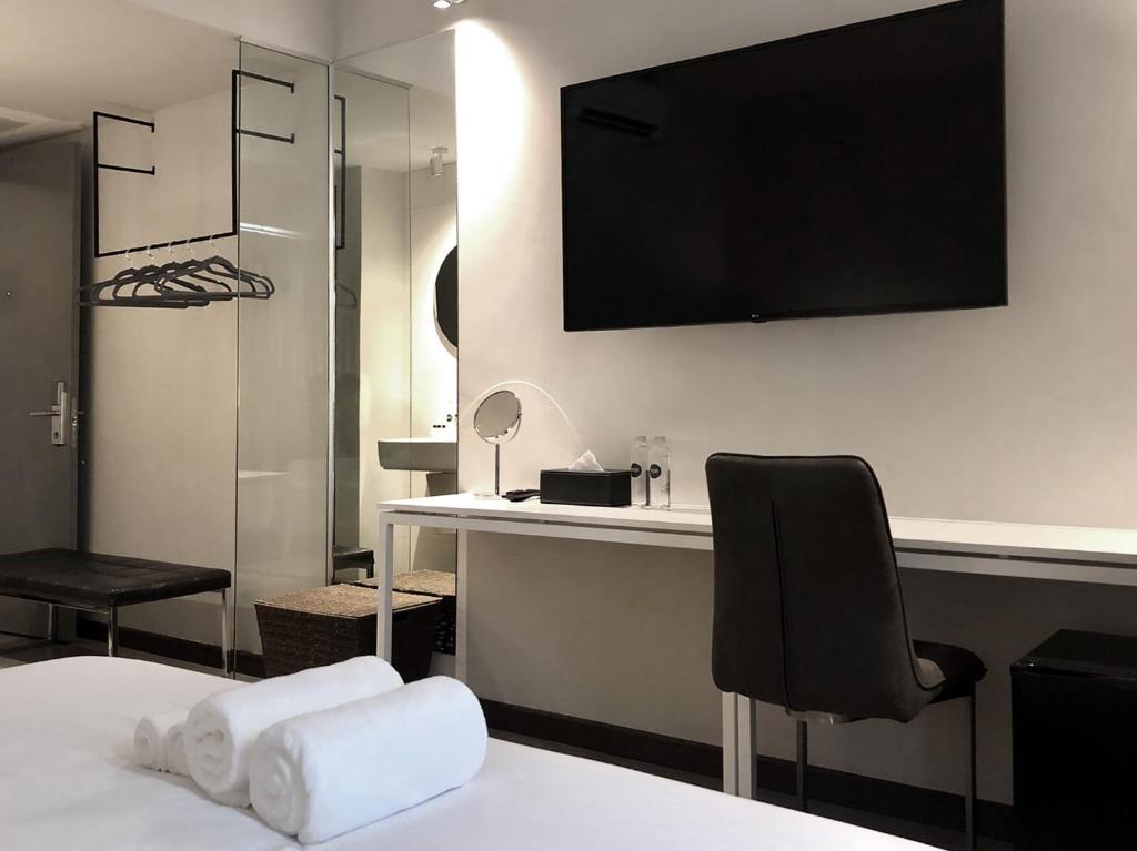 A bed-facing view of the room's desk, chair, television, and open hanging rail.