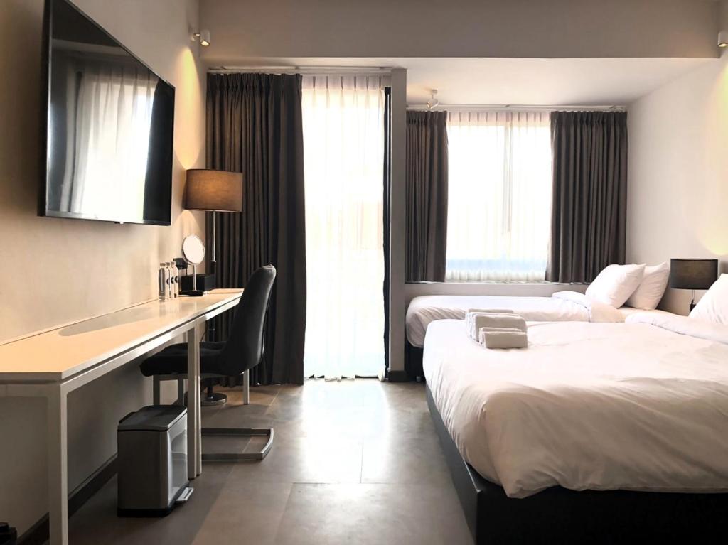 A twin room with two beds, a long desk and a wall-mounted television.