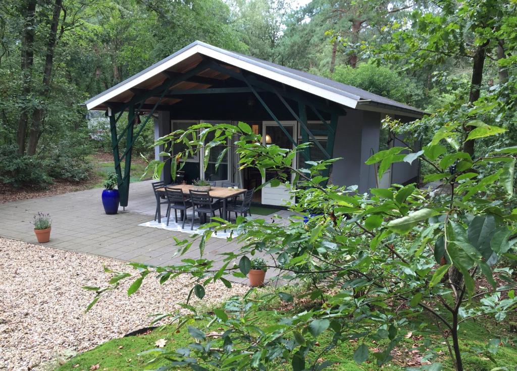 una cabaña en el bosque con mesa y sillas en Het Natuurhuisje op de Veluwe, en Nunspeet