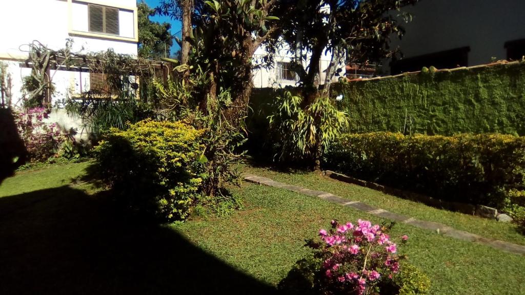 een tuin met een heg en bloemen voor een huis bij Apartamento Jardim Cascata in Teresópolis