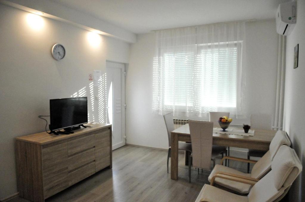 a living room with a television and a dining room table at Rooms LU&LA in Velika Gorica