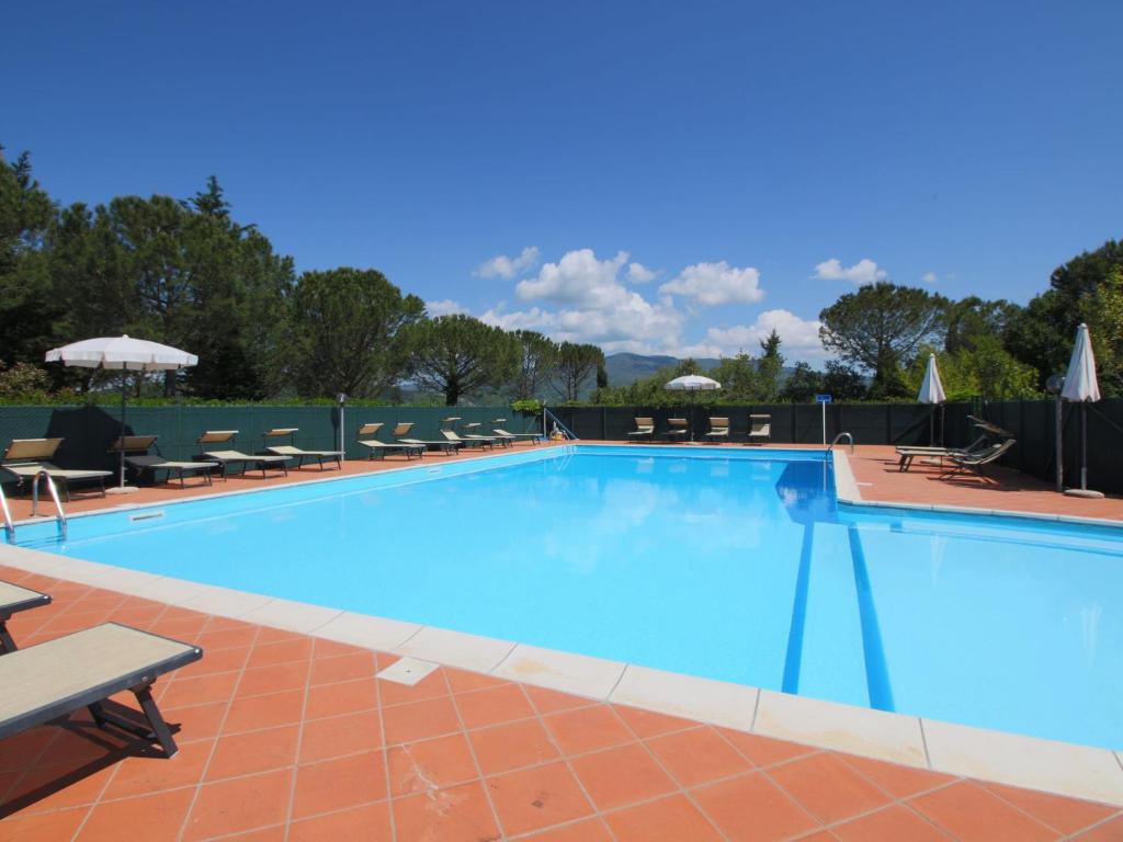 ein großer blauer Swimmingpool mit Stühlen und Sonnenschirmen in der Unterkunft Beautiful Farmhouse with Pool in Arezzo