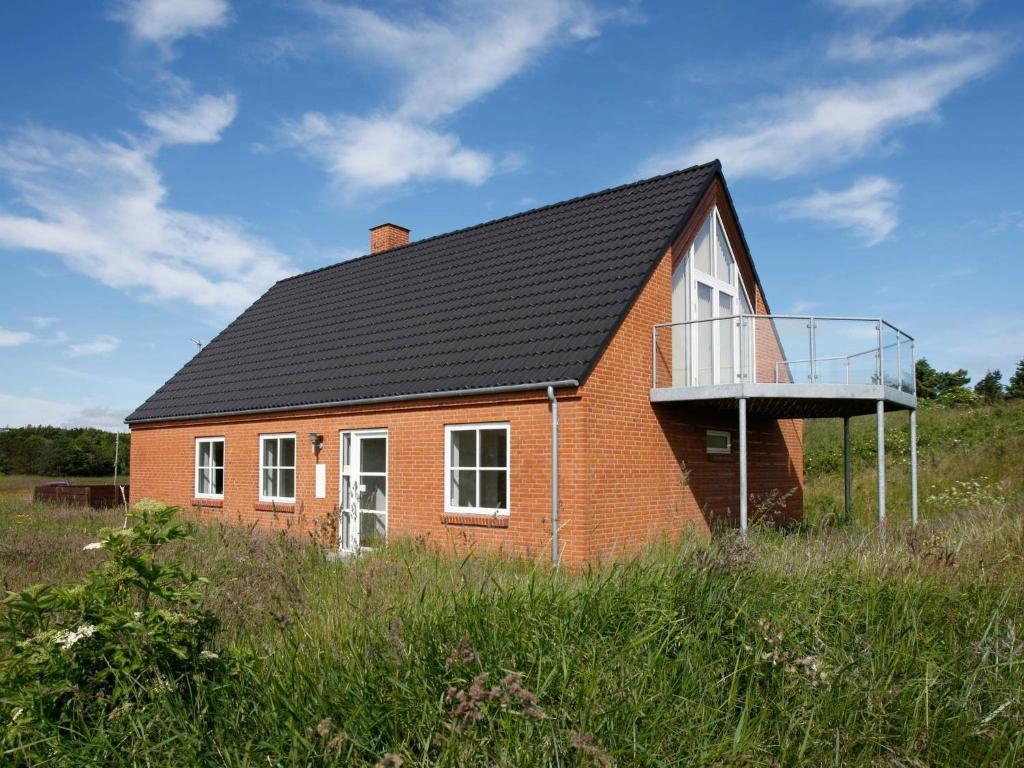 a red house with a black roof and a balcony at Four-Bedroom Holiday home in Hanstholm 3 in Vigsø