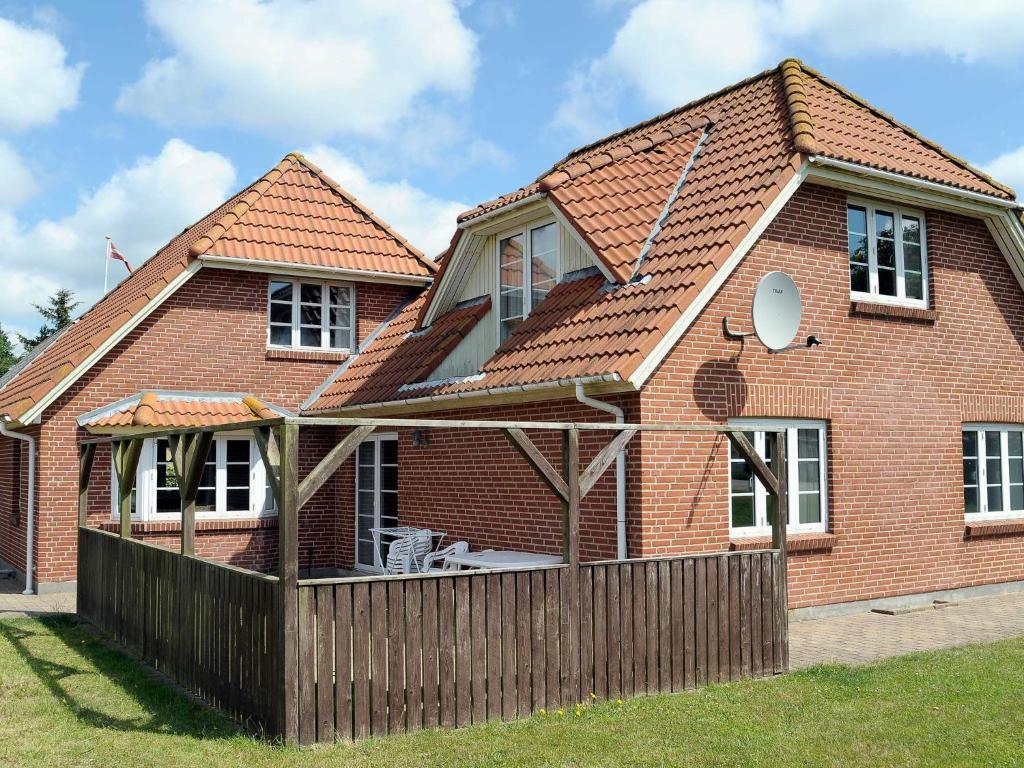 a red brick house with a wooden fence at 14 person holiday home in Bl vand in Ho