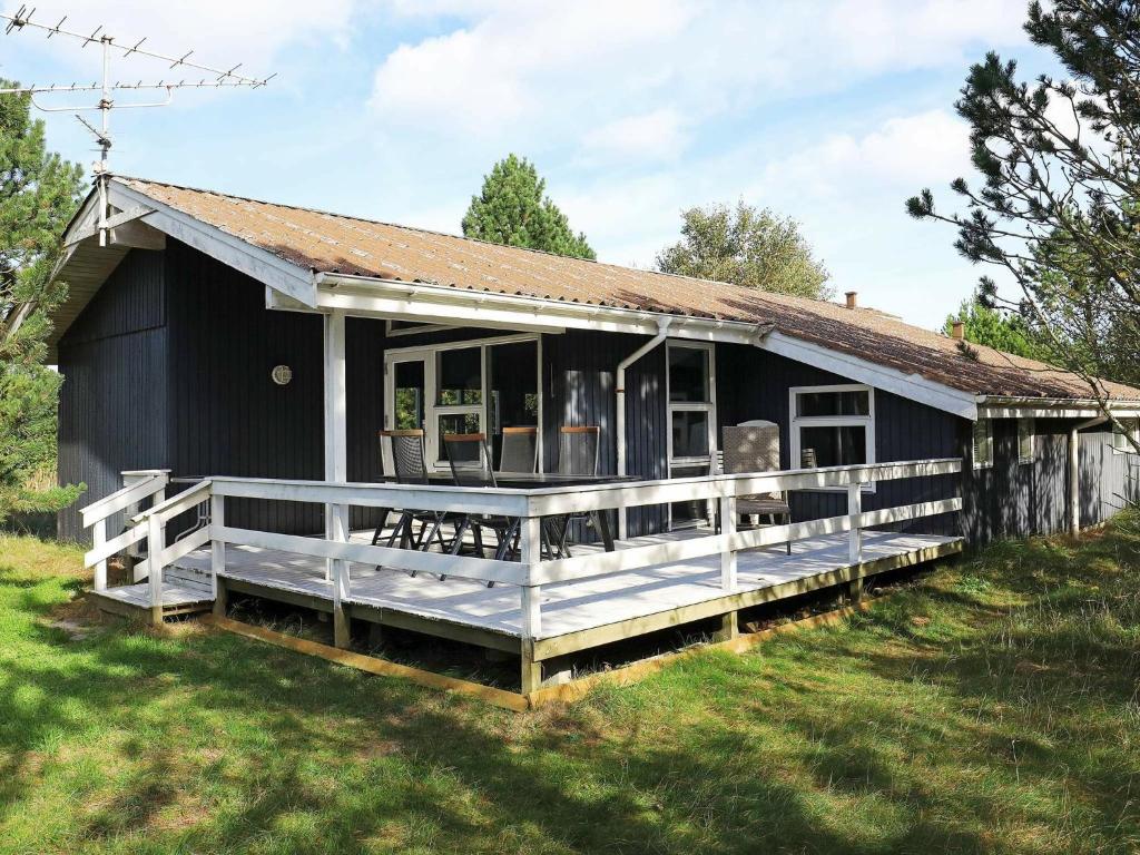 uma casa preta com um grande alpendre num campo em 8 person holiday home in lb k em Ålbæk