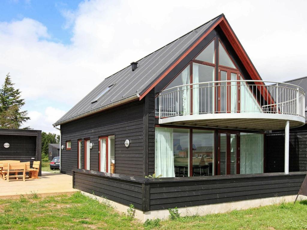 a black house with a balcony and a deck at 8 person holiday home in R m in Rømø Kirkeby