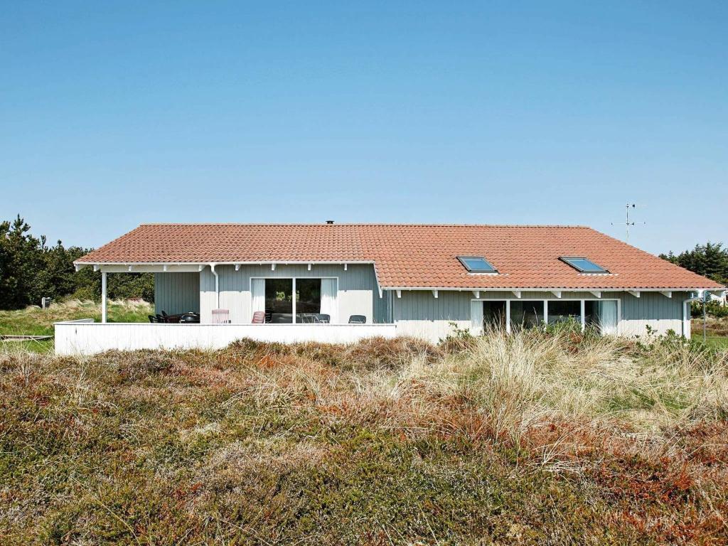 una casa con techo rojo en la parte superior de un campo en 10 person holiday home in Thisted, en Klitmøller