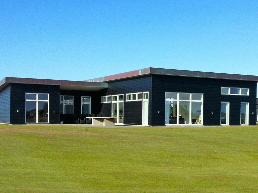 a black building with a grass field in front of it at 18 person holiday home in Løkken-By Traum in Løkken