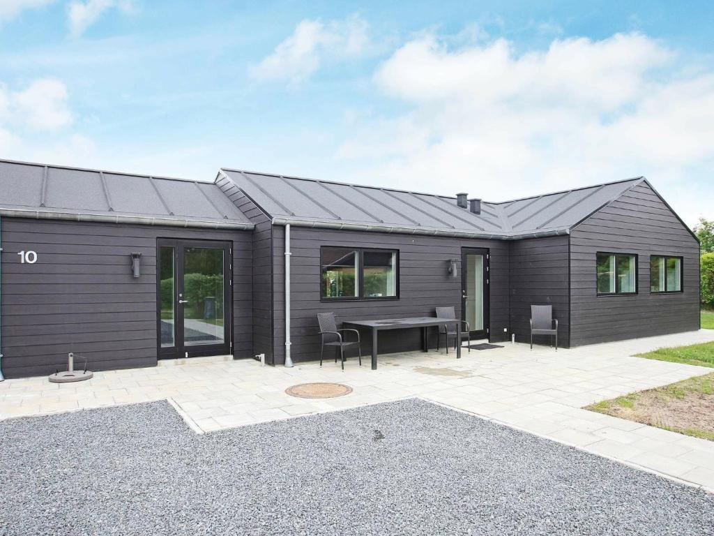 a black house with a patio and a table at Three-Bedroom Holiday home in Tarm 12 in Hemmet