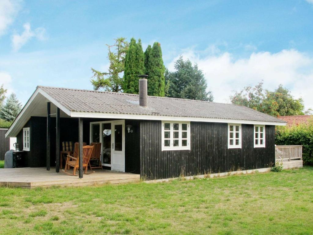 a black and white cottage with a deck at 5 person holiday home in Stege in Stege