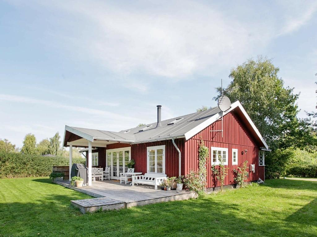 a red house with a porch and a lawn at 8 person holiday home in J gerspris in Jægerspris