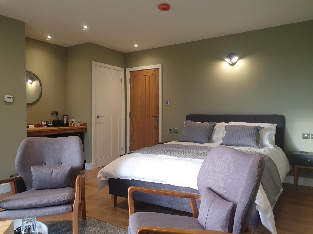 um quarto com uma cama grande e 2 cadeiras em Open acres accommodation and airport parking em Bristol